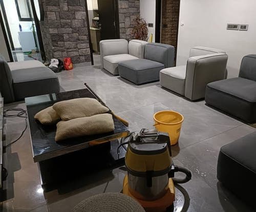 Sofa cushions drying on a table beside a wet vacuum in a living room