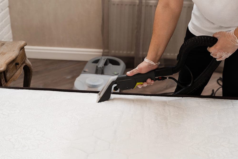 Mattress surface being cleaned with a hand-held extraction tool